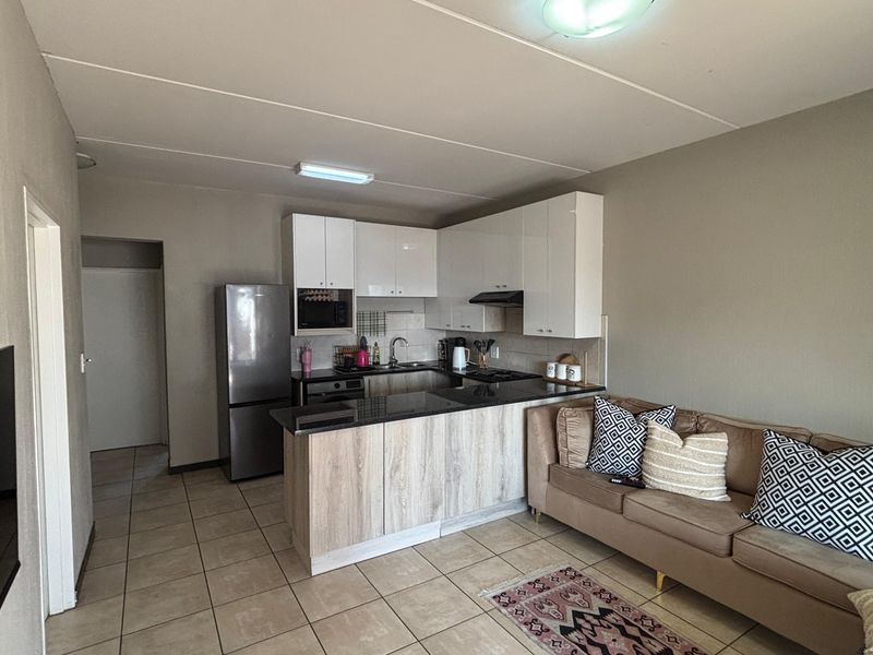 Open-plan living area featuring a modern kitchen with granite countertops, built-in cabinetry, and tiled flooring throughout the space.