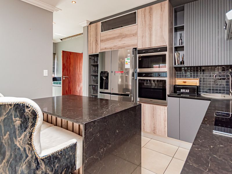 Modern kitchen featuring stone countertops, built-in oven and microwave, sleek cabinetry, and tiled flooring, offering a functional and contemporary cooking space.