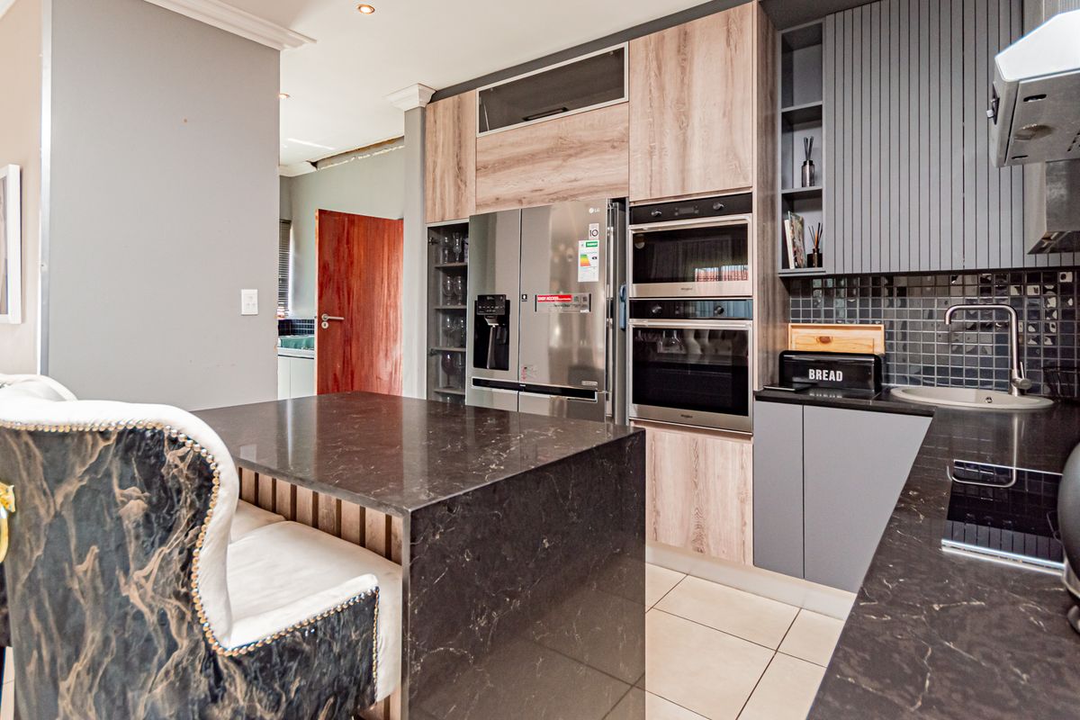 Modern kitchen featuring stone countertops, built-in oven and microwave, sleek cabinetry, and tiled flooring, offering a functional and contemporary cooking space.