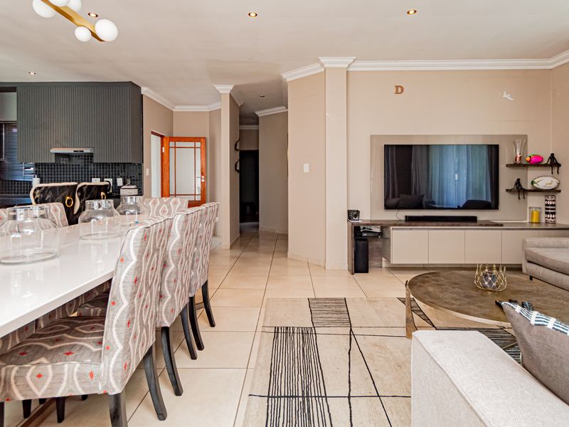 Spacious open-plan living and dining area featuring tiled floors, recessed lighting, and a modern kitchen with integrated appliances and sleek cabinetry.