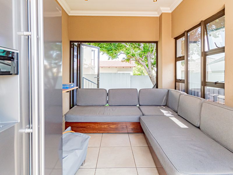 A bright, enclosed patio area featuring tiled flooring, recessed lighting, and large bi-fold doors that open to the garden.