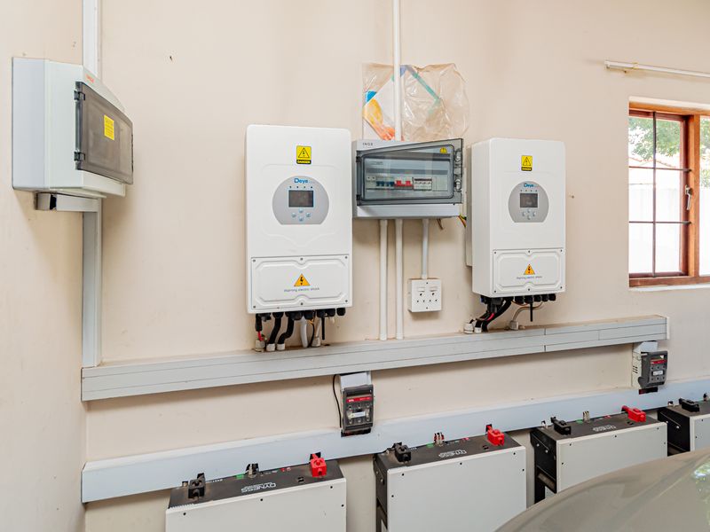 Garage space featuring a modern solar power installation with dual inverters and a battery storage system.