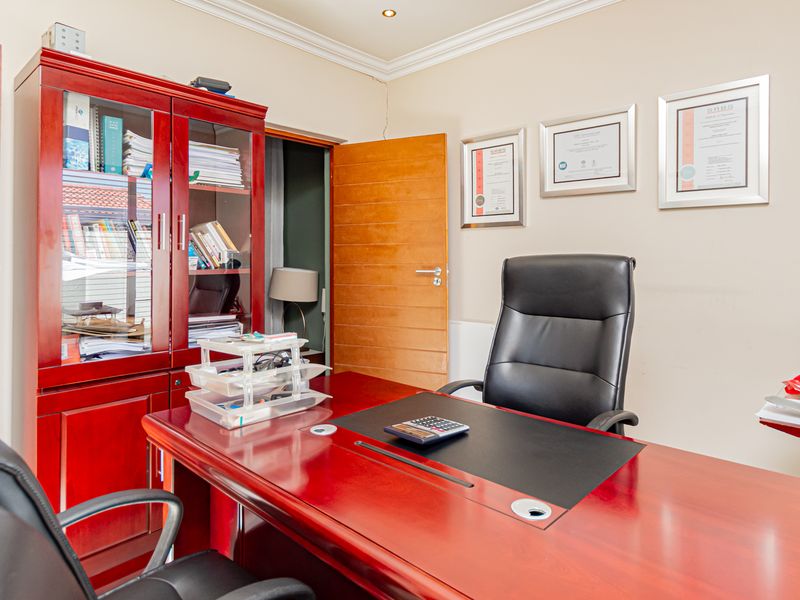 A functional home office space featuring neutral walls, recessed ceiling lighting, and solid timber doors.