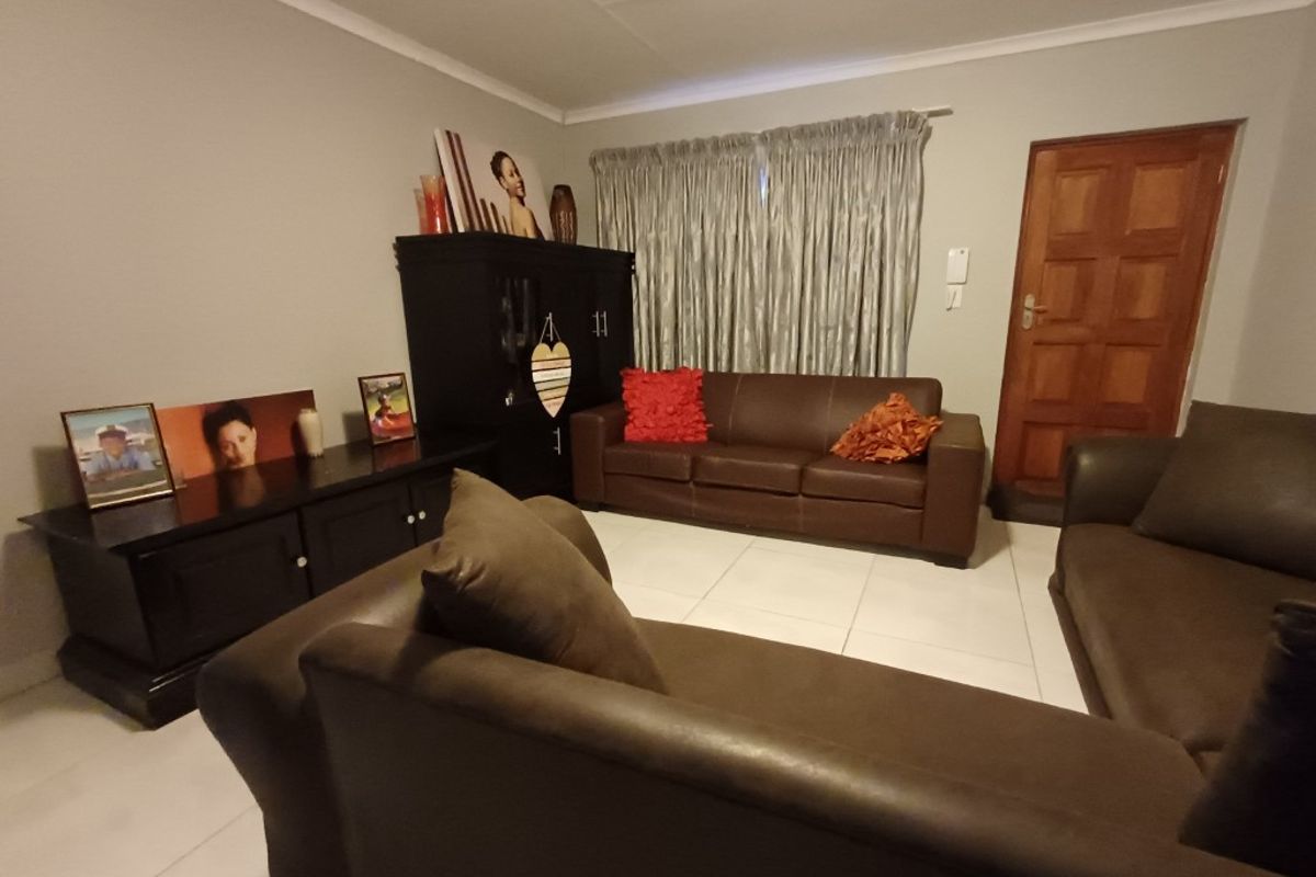 A comfortable living room featuring tiled flooring, neutral wall finishes, and a solid timber entrance door.