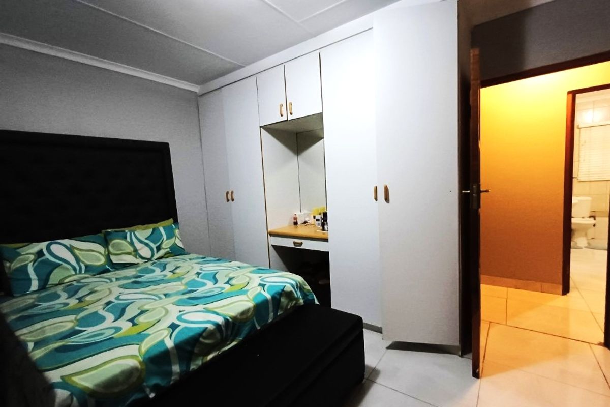 Bedroom featuring built-in cupboards with integrated vanity area, tiled flooring, and direct access to an adjacent bathroom.