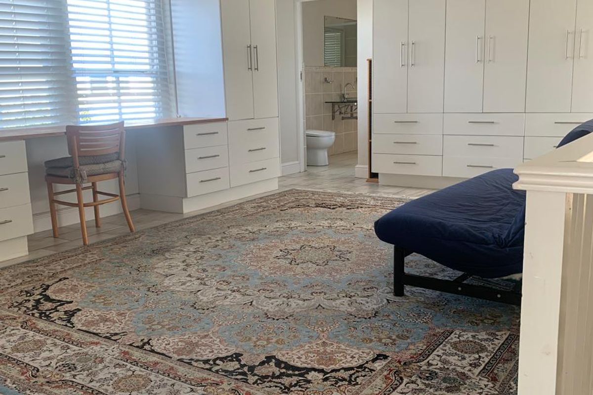 Spacious bedroom featuring extensive built-in cabinetry, a dedicated desk area, tiled flooring, and an en-suite bathroom.