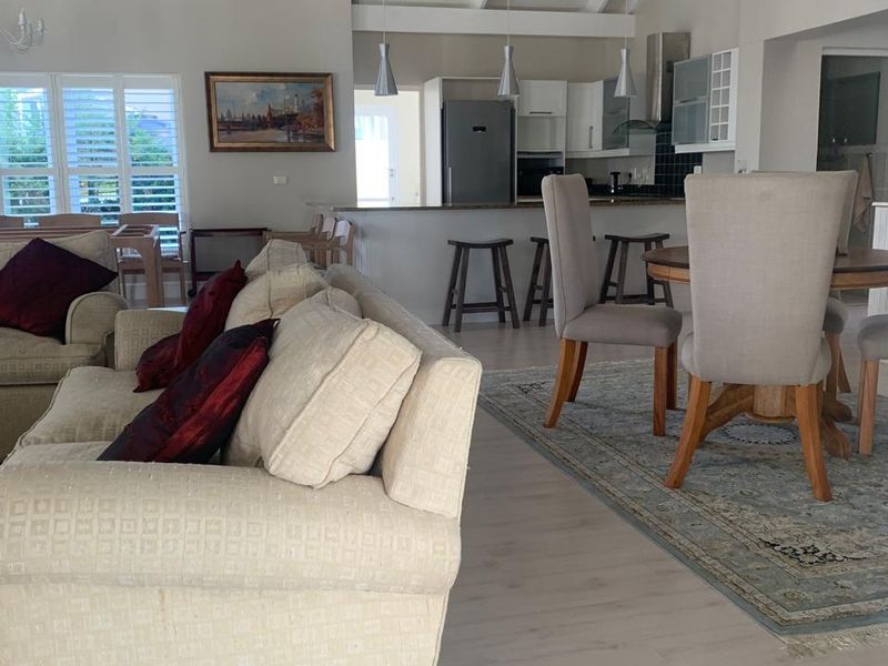 Spacious open-plan living and kitchen area featuring vaulted ceilings with exposed beams, laminate flooring, and a functional kitchen island with breakfast bar seating.