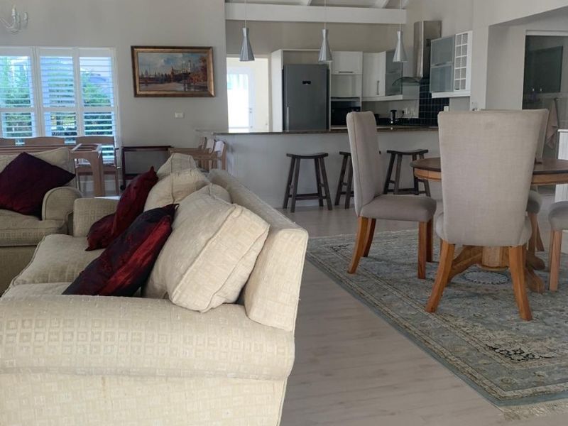 Spacious open-plan living and kitchen area featuring vaulted ceilings with exposed beams, modern cabinetry, and light laminate flooring throughout.