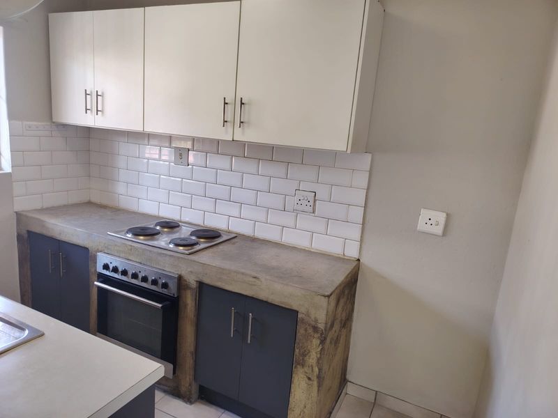 A functional kitchen featuring concrete countertops, subway tile backsplash, built-in oven and hob, and modern two-tone cabinetry.