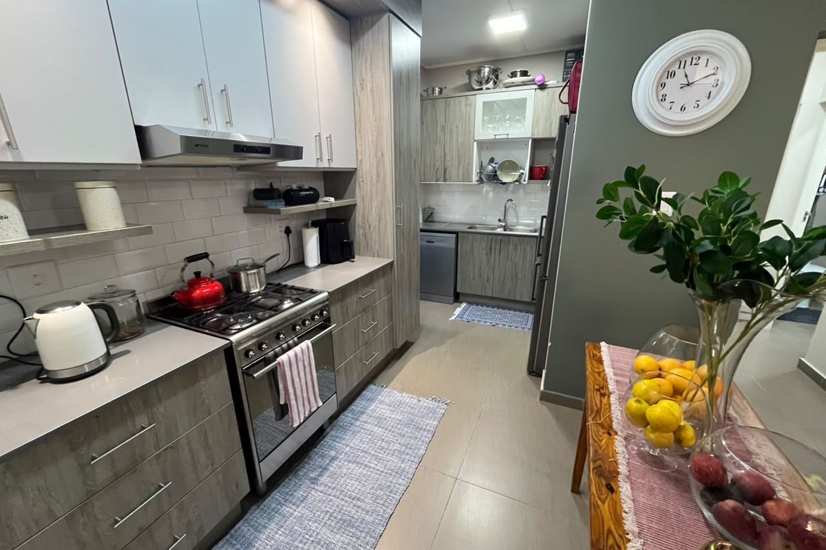 Modern kitchen featuring wood-grain cabinetry, gas stove with extractor fan, tiled backsplash, and integrated dishwasher, offering a functional and contemporary cooking space.