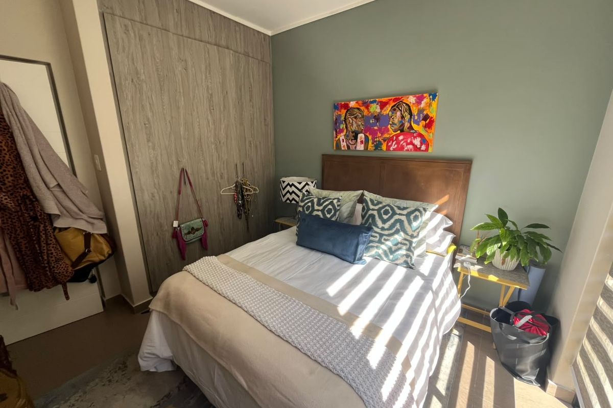 A well-maintained bedroom featuring built-in cupboards with a wood-grain finish and a feature wall, offering a functional and comfortable living space.