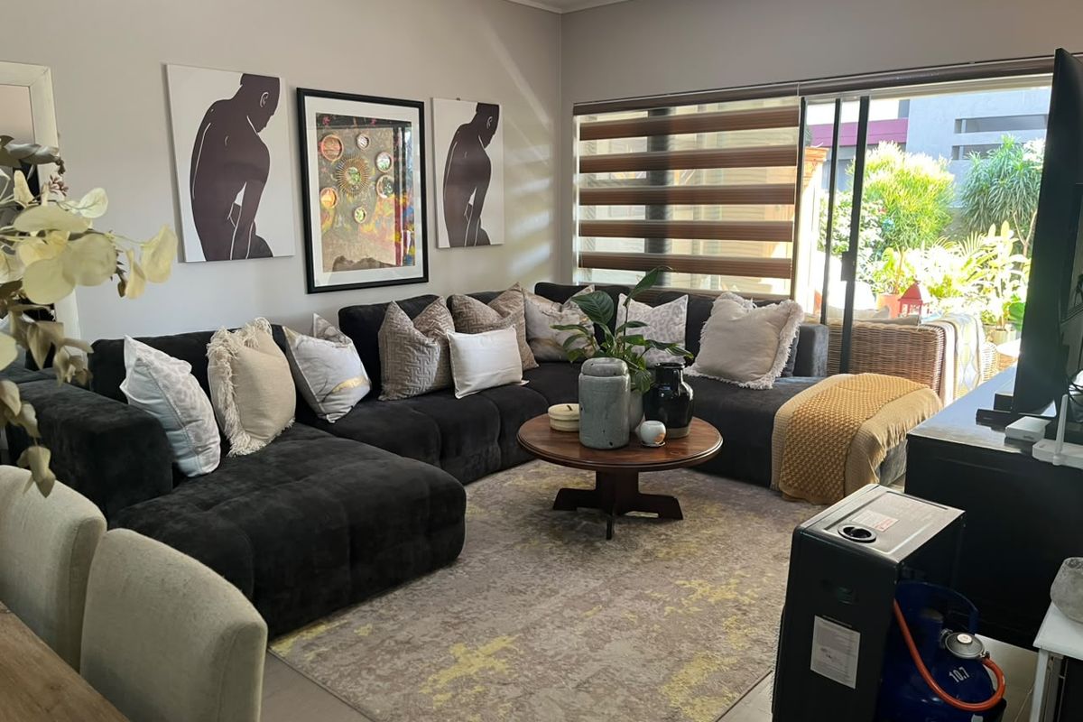 A comfortable living room featuring tiled flooring and large sliding glass doors that provide access to an outdoor patio area.