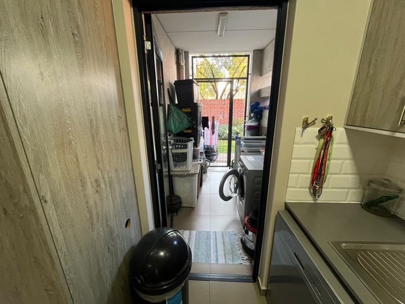 A functional laundry area featuring tiled flooring and direct access to an outdoor space, providing practical utility and storage potential.