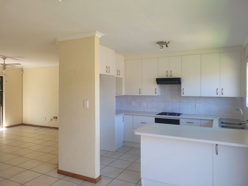 Open-plan kitchen and living area featuring white cabinetry, tiled flooring, and a functional layout, offering a blank canvas for modern updates.