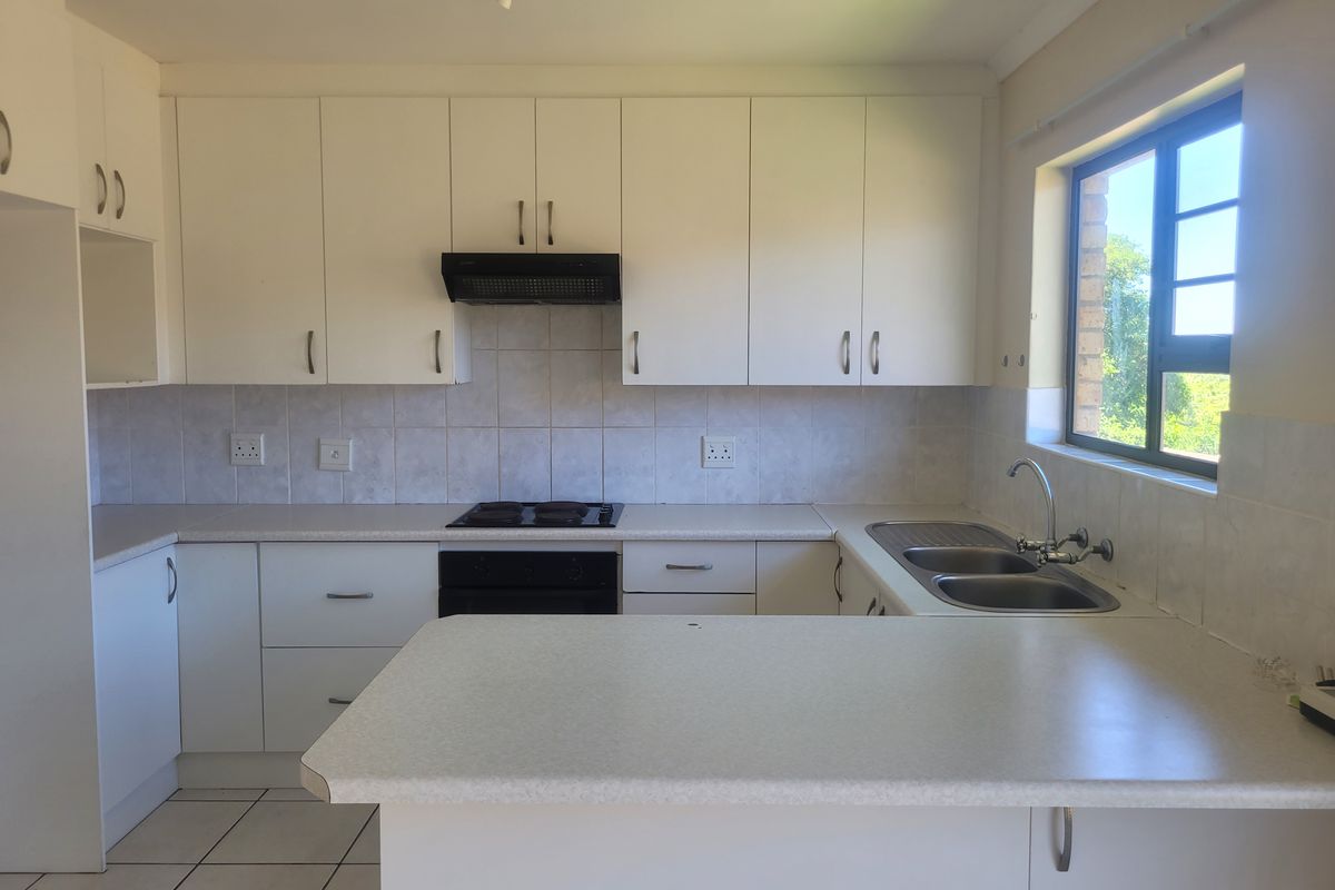 A functional kitchen featuring white cabinetry, laminate countertops, a built-in oven with hob, and a double bowl sink with tiled backsplash.