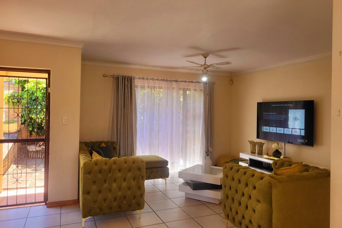 A comfortable living room featuring tiled flooring, a ceiling fan, and a sliding glass door providing access to the exterior.
