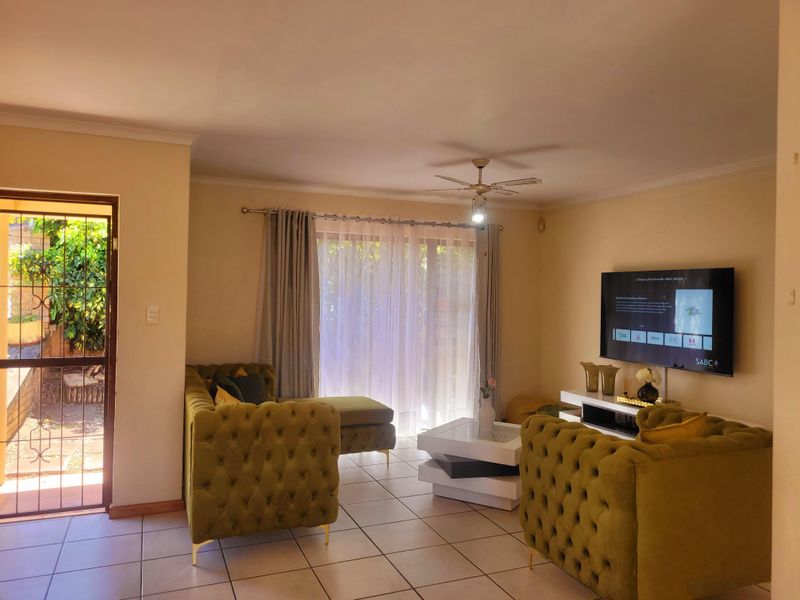 A comfortable living room featuring tiled flooring, a ceiling fan, and a sliding glass door providing access to the exterior.
