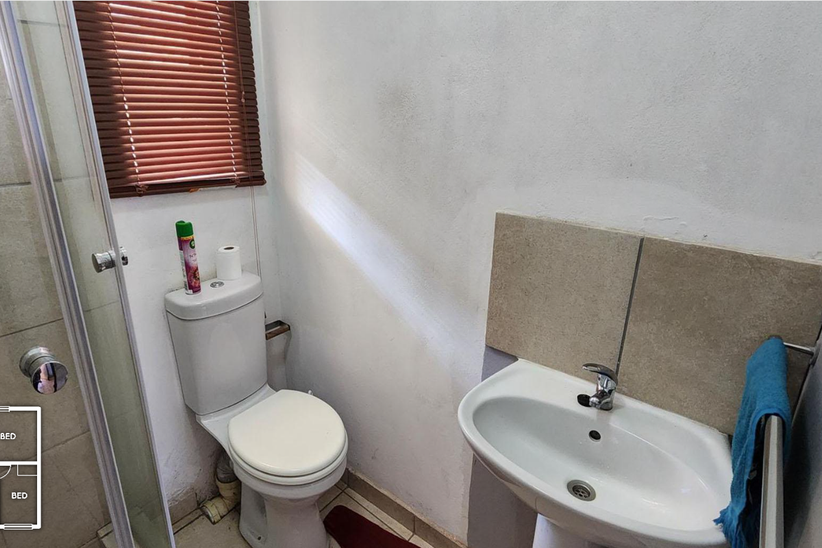 Compact bathroom featuring a shower enclosure, pedestal basin with mixer tap, and tiled splashback, requiring minor cosmetic attention to wall finishes.