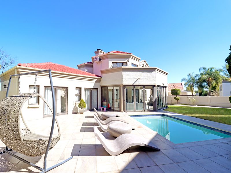 Rear view of the property featuring a tiled patio, swimming pool, and access to the interior through large sliding glass doors.