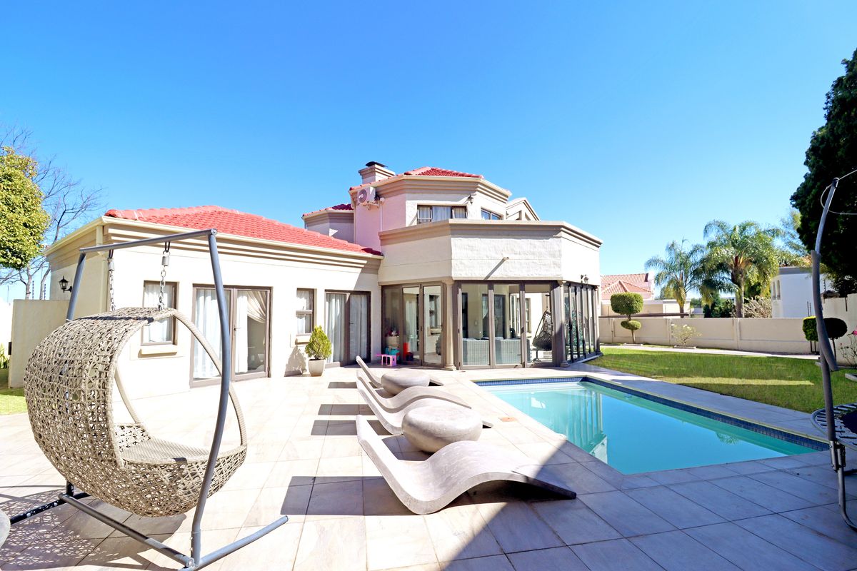 Rear view of the property featuring a tiled patio, swimming pool, and access to the interior through large sliding glass doors.