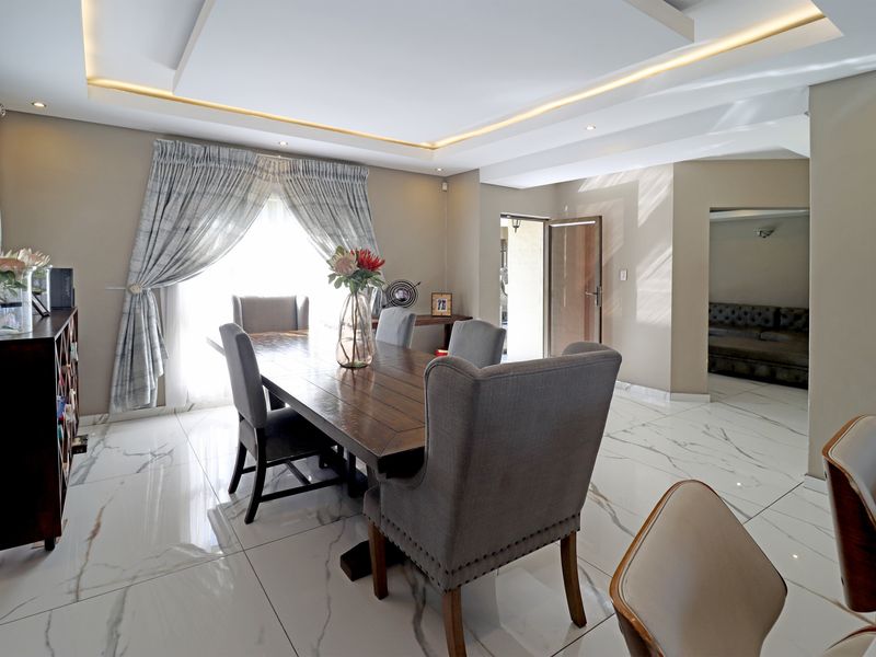 Elegant dining room featuring high-quality marble-look floor tiles and a sophisticated recessed ceiling with integrated ambient LED lighting.