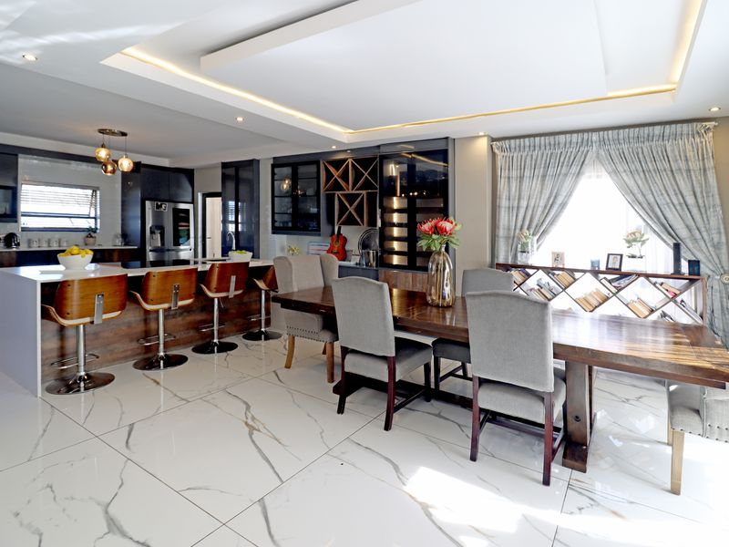 Modern open-plan living and dining area featuring high-end marble-look floor tiles, a sleek kitchen island, and sophisticated recessed ceiling lighting.