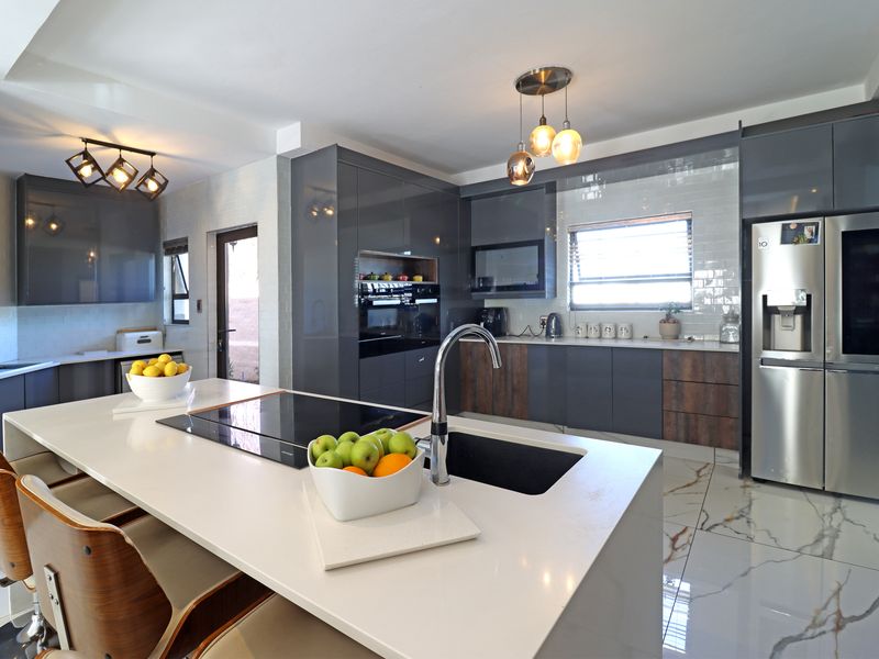 Modern kitchen featuring a central island with induction hob, sleek gloss cabinetry, subway tile backsplash, and high-end marble-look floor tiles.