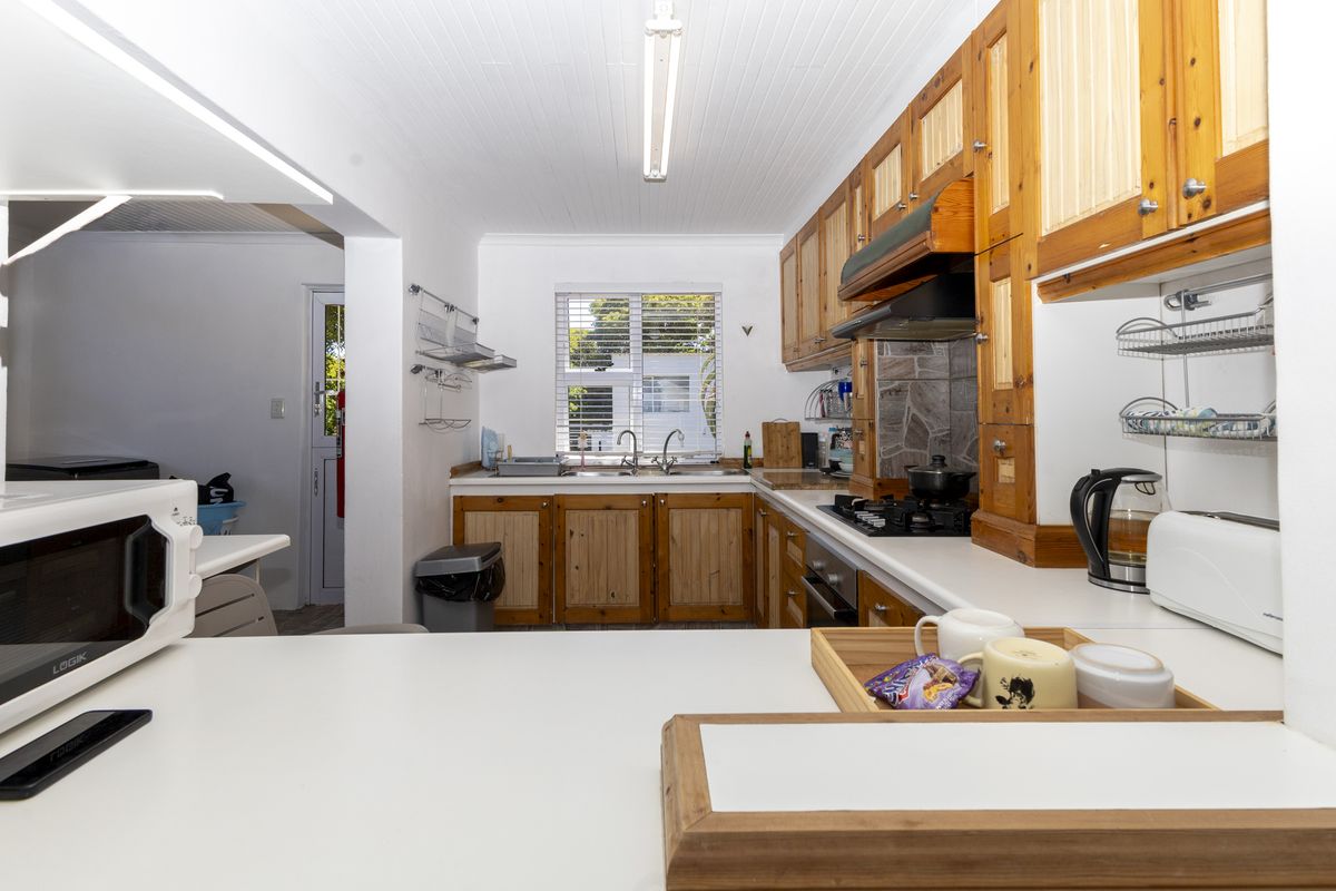 A functional kitchen featuring wooden cabinetry, gas hob, built-in oven, and double sink with a bright, clean layout.