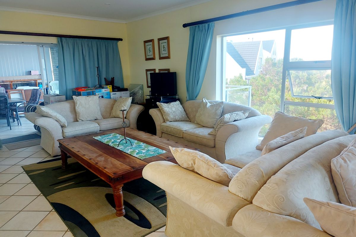 A spacious living room featuring large windows, tiled flooring, and direct access to an adjoining patio area.