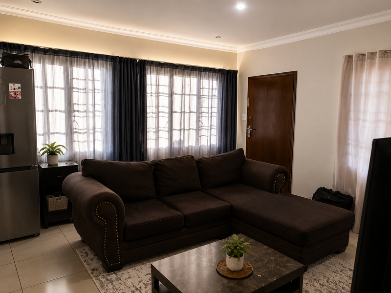 A comfortable living room featuring tiled flooring, recessed downlighting, and decorative cove cornicing, providing a neutral and functional space.