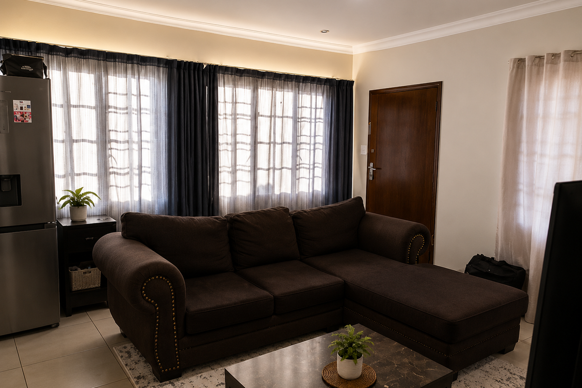 A comfortable living room featuring tiled flooring, recessed downlighting, and decorative cove cornicing, providing a neutral and functional space.