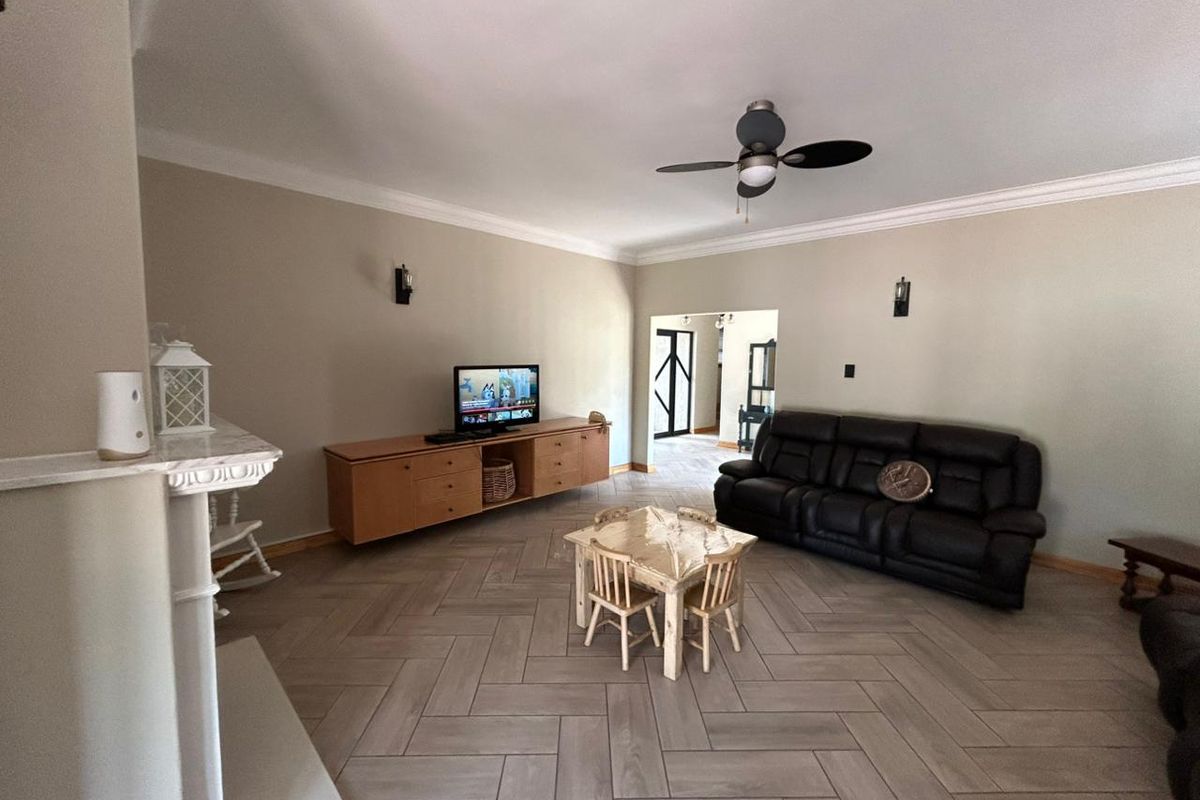 Spacious living room featuring herringbone tile flooring, cove cornicing, and a fireplace mantel, offering a neutral backdrop for comfortable family living.