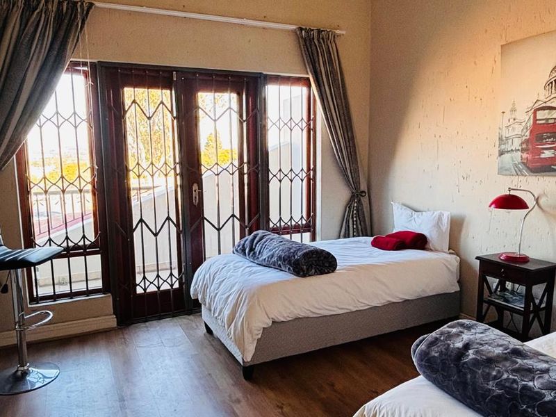 A bedroom featuring laminate flooring and access to a balcony through secure french doors.