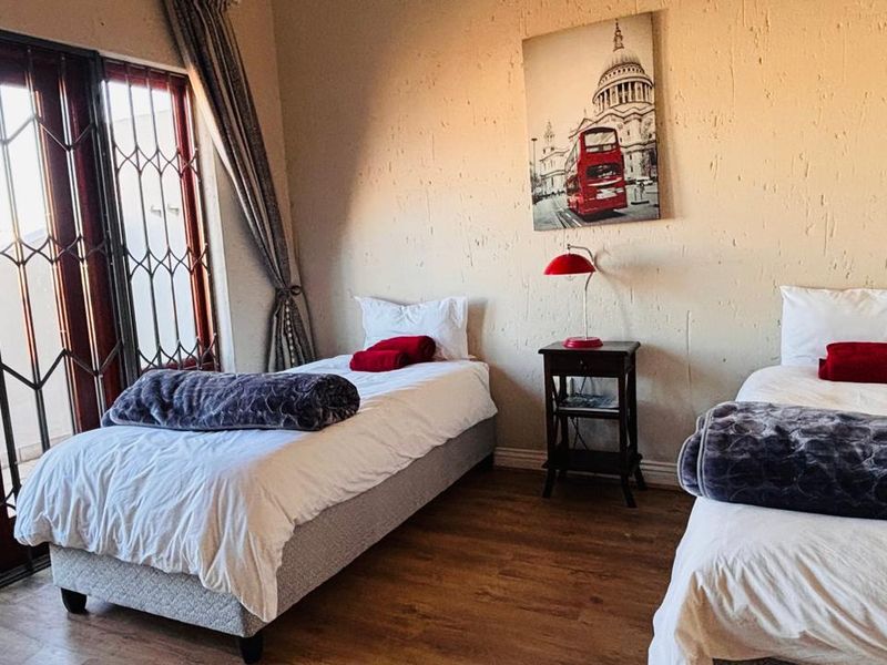 A bedroom featuring laminate flooring, textured walls, and a sliding door with a security gate leading to an outdoor area.