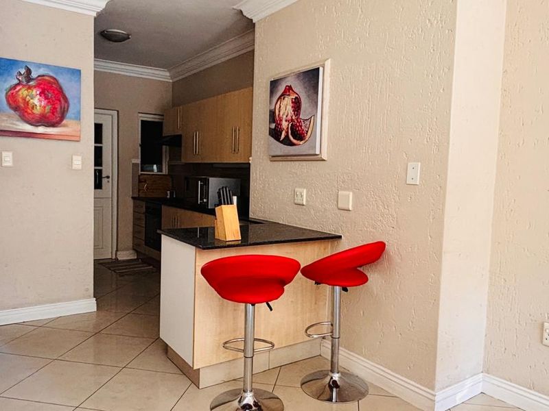 Open plan kitchen area featuring light wood cabinetry, granite countertops, and tiled flooring, seamlessly connecting to the living space.