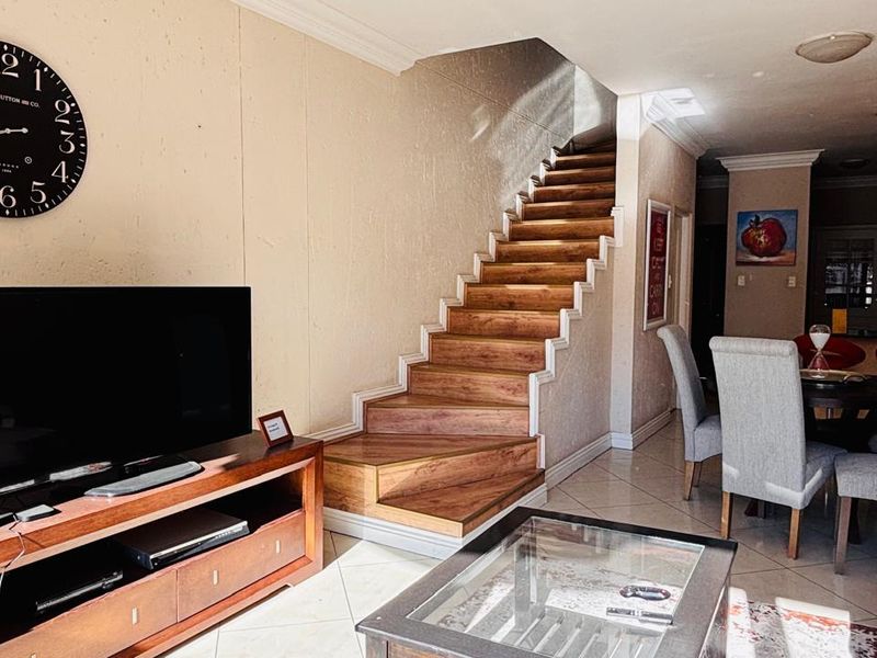 Open plan living and dining area featuring a wooden staircase, tiled flooring, and crown molding, creating a functional and connected living space.