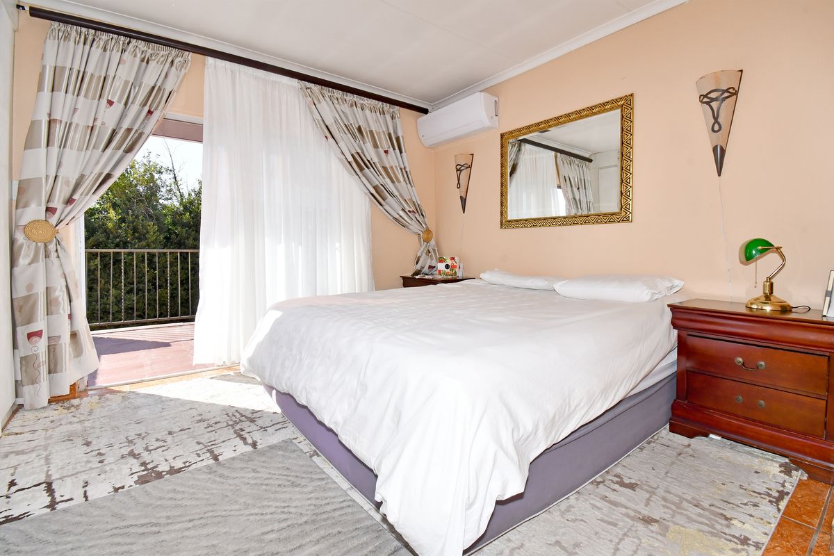 A bedroom featuring a split-system air conditioner and direct access to an outdoor balcony through a sliding glass door.
