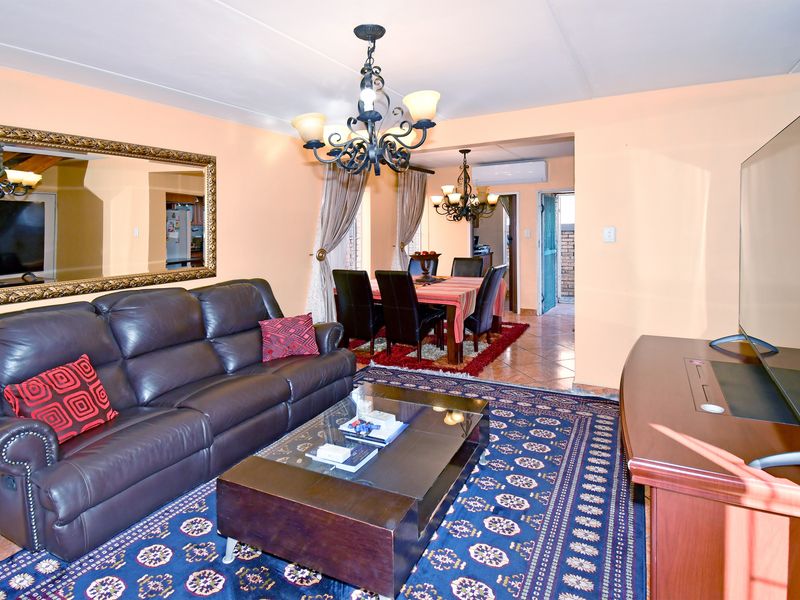 Open plan living and dining area featuring tiled flooring, a split system air conditioner, and traditional chandelier lighting.