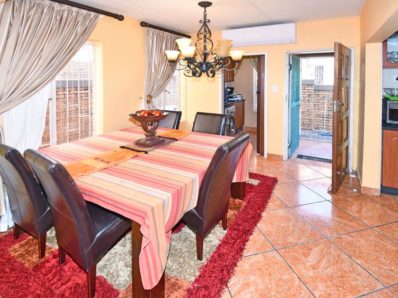 Dining area featuring tiled flooring, a wrought iron chandelier, and a split-system air conditioner, with direct access to the kitchen and exterior.