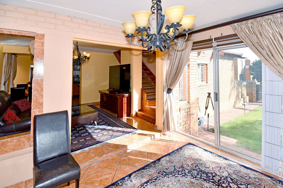 Living room featuring tiled flooring, a wooden staircase, and large sliding glass doors providing direct access to the rear garden area.