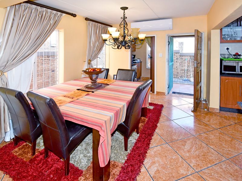 Open-plan dining area featuring ceramic floor tiles, a split-system air conditioner, and direct access to an outdoor courtyard, adjacent to a functional kitchen.