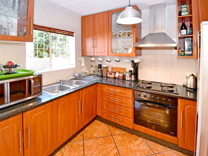 A functional kitchen featuring wood-finish cabinetry, granite countertops, a built-in oven with hob, and a double stainless steel sink.
