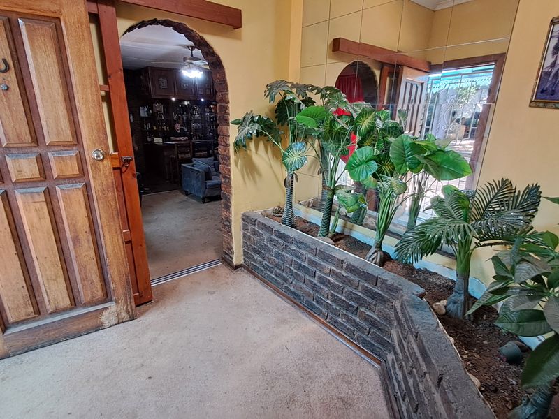 Entrance foyer featuring a built-in brick planter box, mirrored wall accents, and an arched doorway leading into the living area.