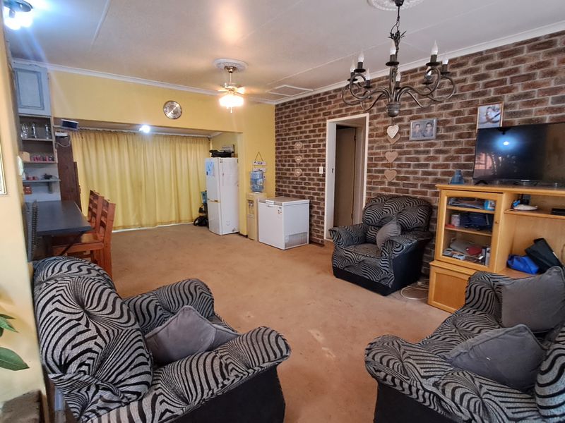 Open plan living area featuring an exposed brick feature wall, decorative ceiling lighting, and carpeted flooring.