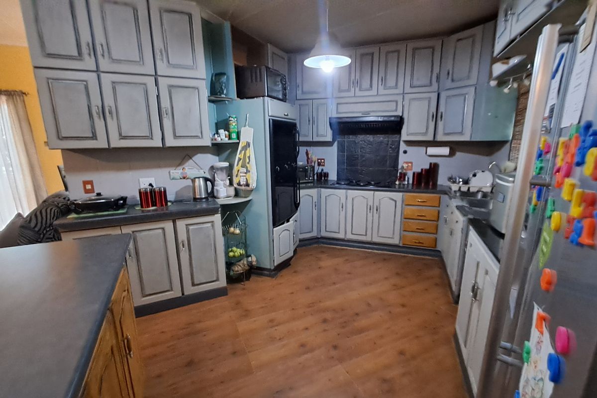 A functional kitchen featuring extensive built-in cabinetry, laminate countertops, and integrated appliances, offering a practical layout with potential for modern cosmetic updates.