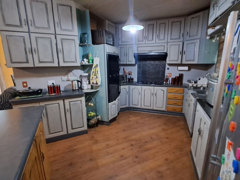 A functional kitchen featuring extensive built-in cabinetry, laminate countertops, and integrated appliances, offering a practical layout with potential for modern cosmetic updates.