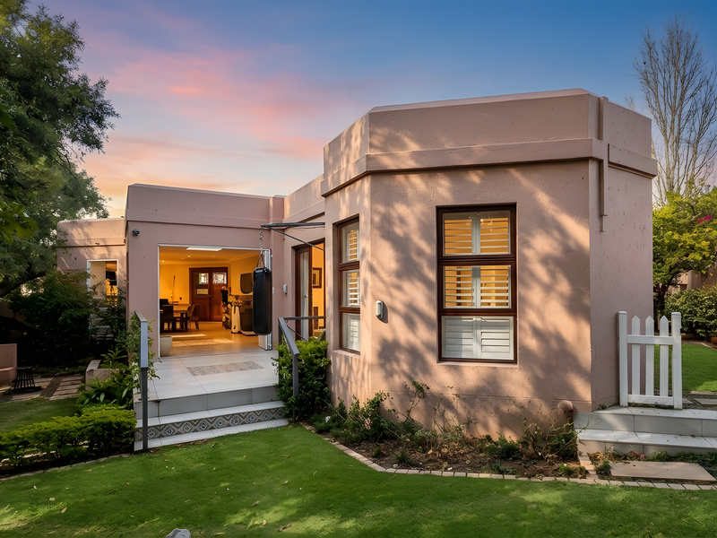 Rear view of the townhouse featuring a landscaped garden, tiled patio area, and modern exterior finishes with large windows.