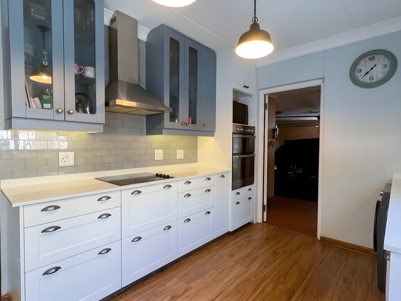 Modern kitchen featuring two-tone cabinetry, subway tile backsplash, quartz countertops, and integrated stainless steel appliances, including a double oven and electric hob.