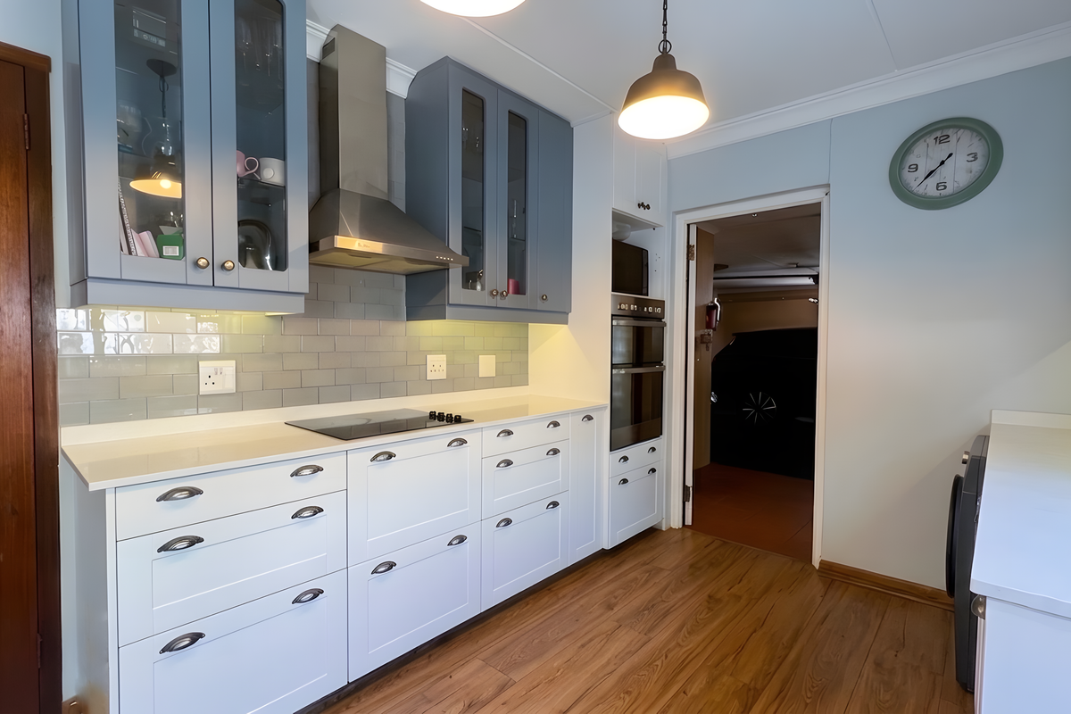 Modern kitchen featuring two-tone cabinetry, subway tile backsplash, quartz countertops, and integrated stainless steel appliances, including a double oven and electric hob.