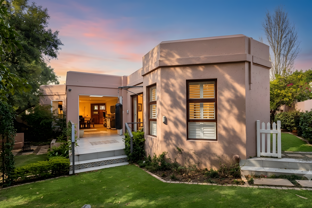 Rear view of the townhouse featuring a landscaped garden, tiled patio area, and modern exterior finishes with large windows.